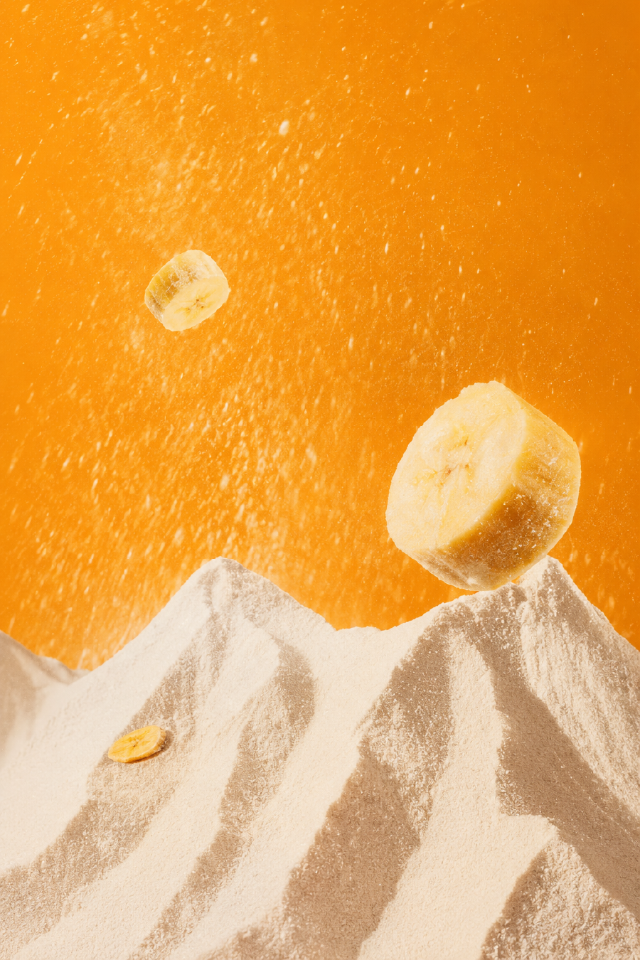 Rodajas de banana y harina sobre un fondo naranja
